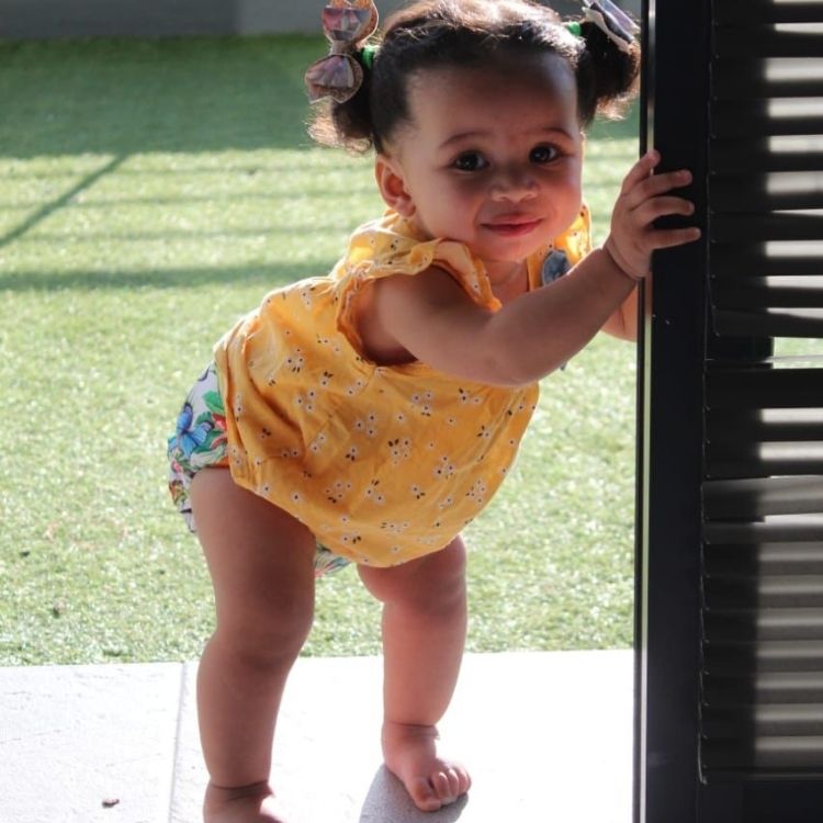 A baby standing in a doorway wearing a reusable cloth nappy