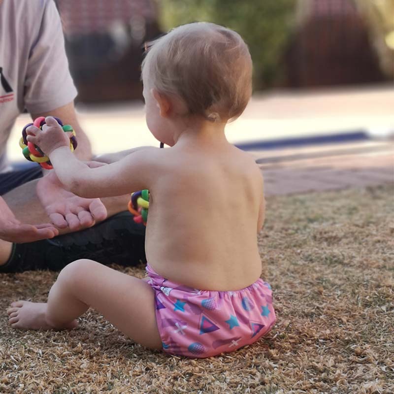 A toddler girl in a cloth nappy playing with her father