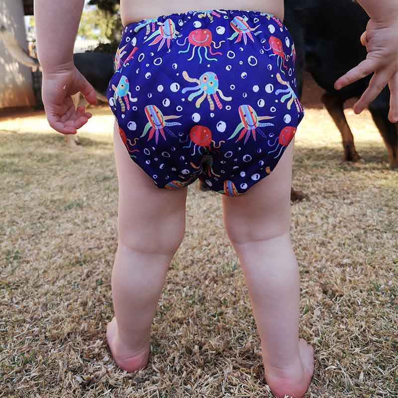 A toddler wearing a blue octopus pattern reusable cloth nappy