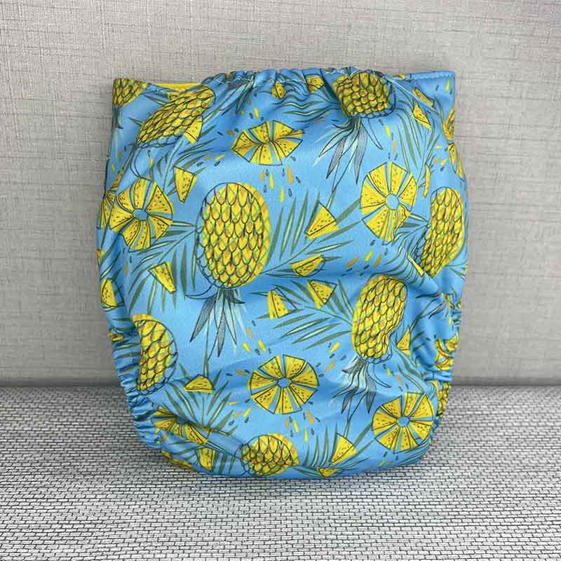 Back view of a bright cloth diaper with yellow wings, pineapples and a blue background