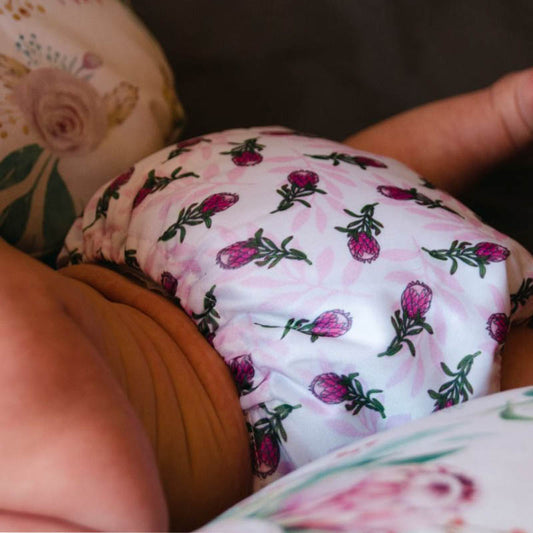 A baby wearing a reusable nappy with a protea pattern