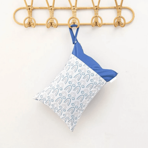 A blue wet bag with rainbows hanging from a hook