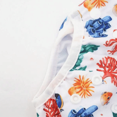 Close up of a swim nappy with patterns of reefs, fish, seahorses, octopi and more.
