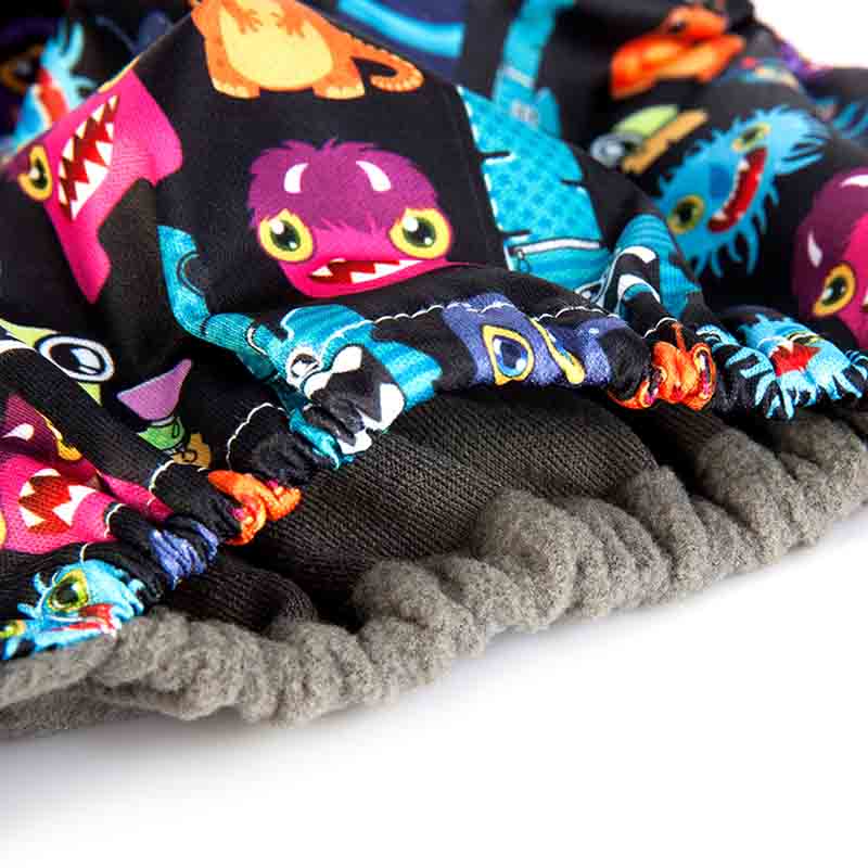 Close up a reusable diaper with a colourful monsters patter